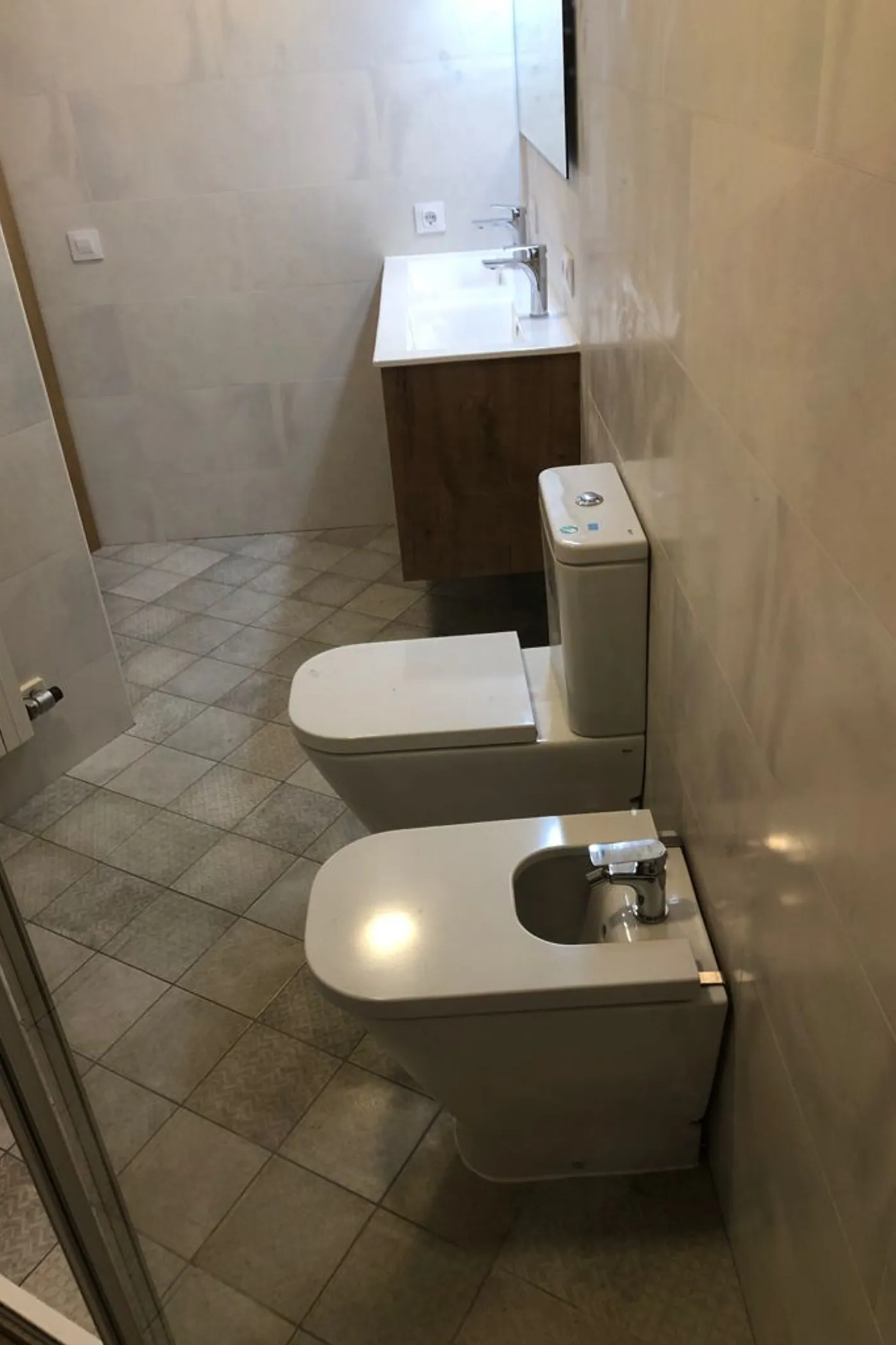 Vista general del bany acabat amb inodor, bidet i paviment hidràulic
