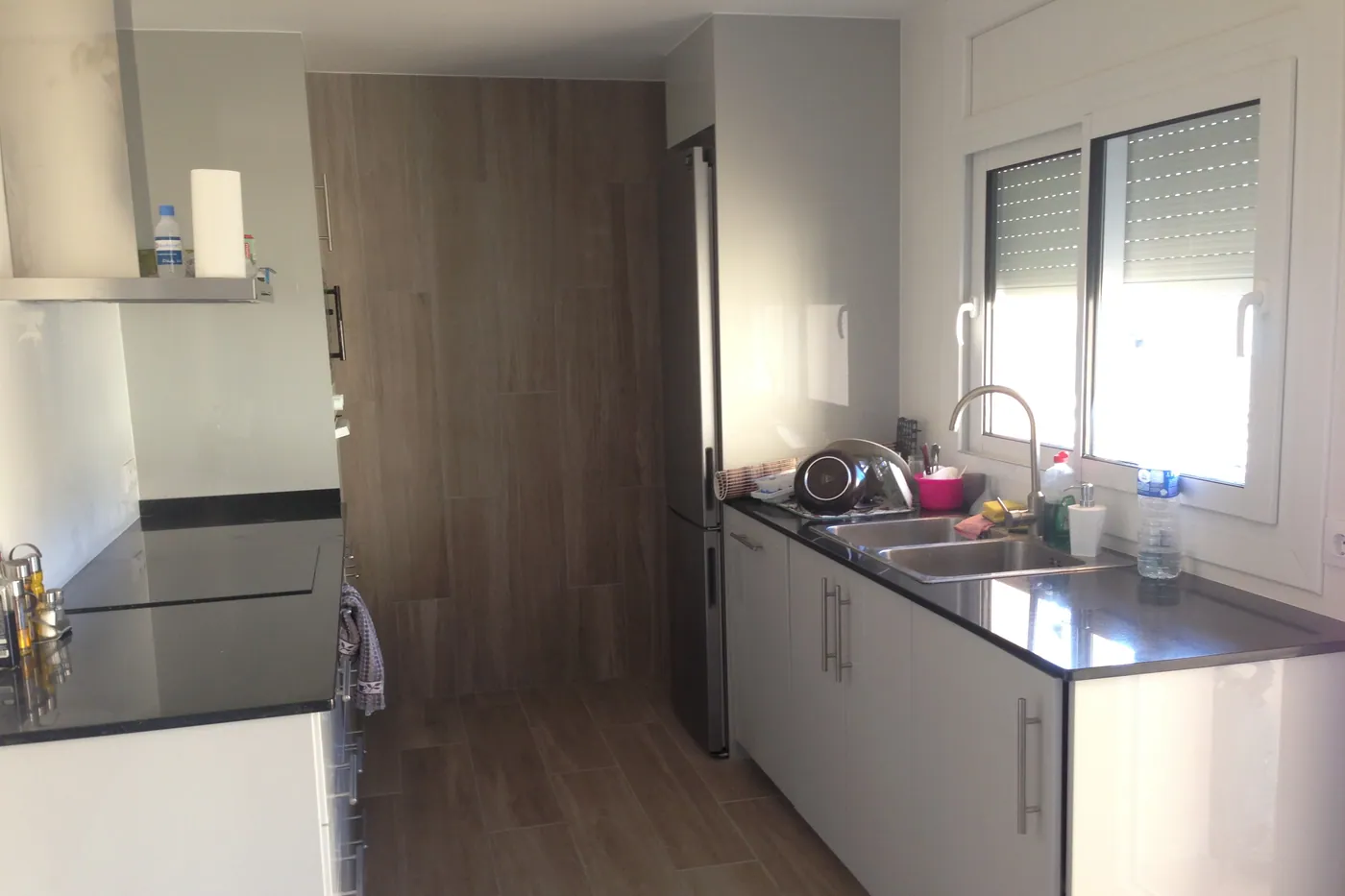 Cuina en línia amb front blanc, taulell fosc i paviment de fusta ceràmica