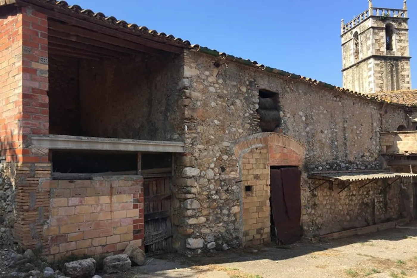 Façana de mur de còdols de riu amb pallissa i arcs de maó