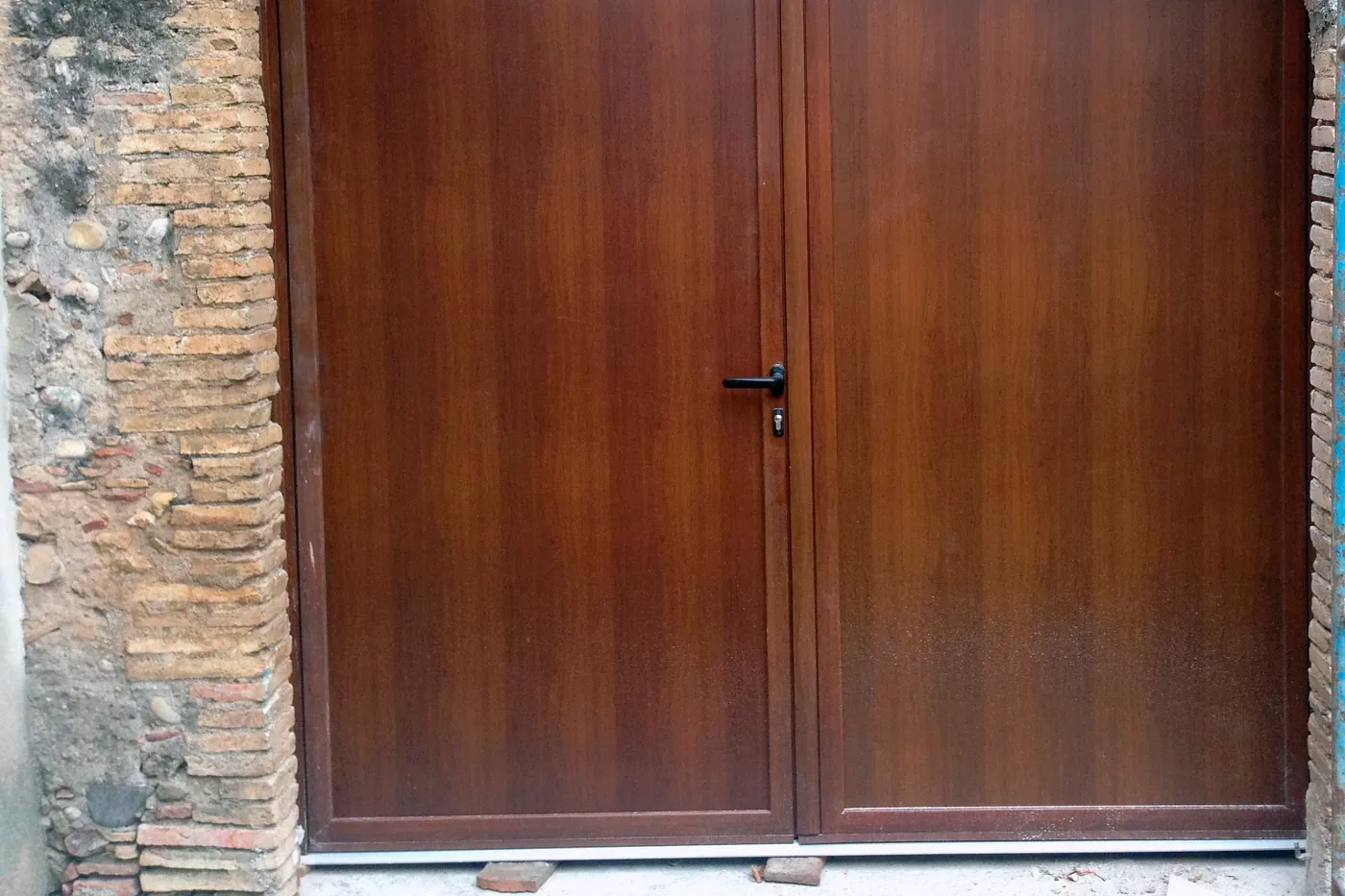Porta de dues fulles nova sota arc rebaixat de maó massís restaurat